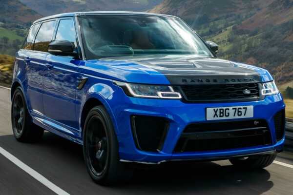 A blue Range Rover Sport drives along a scenic road, showcasing its sleek design against a backdrop of rolling hills.