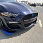 A close-up of a dark blue modified Ford Mustang gt with a sleek front design, featuring a black grille and blue accents on the lip and stripes.