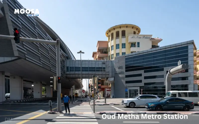 Oud Metha Metro Station showcased with modern architecture and surrounding buildings, featuring traffic signals and pedestrians.