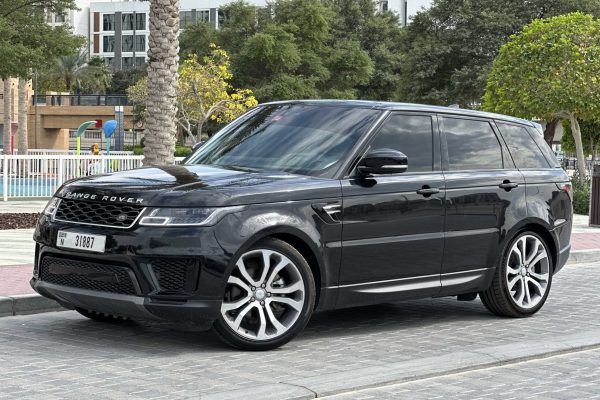 A sleek black Range Rover parked on a stone pathway, surrounded by greenery and colorful playground equipment in the background.